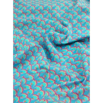 Close-up of Carnivale cotton fabric featuring a vibrant, geometric feather-inspired pattern in teal, orange, and yellow on a soft cotton base.