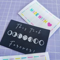 Woven sew-in labels; one in black with the words 'This Took Forever' and the other in white with the words 'Made with Love' in rainbow colours